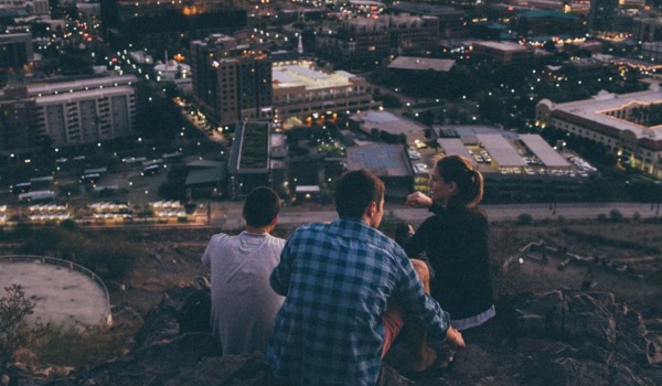 a group of people sitting on a hill overlooking a city