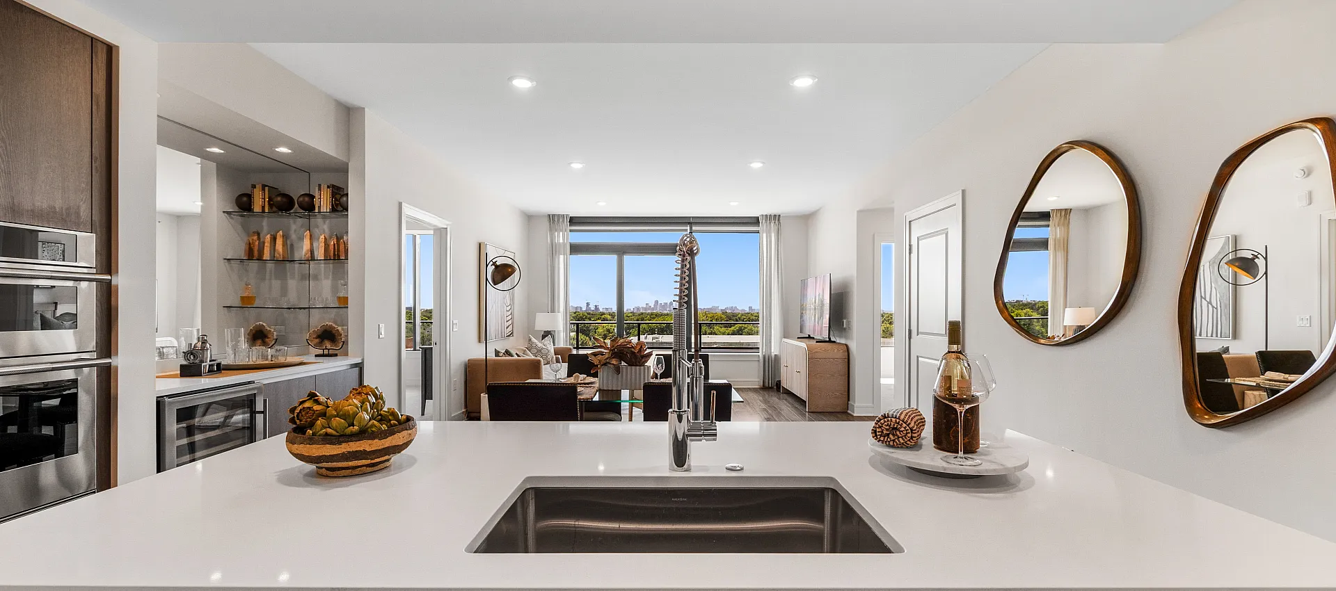 Modern open-concept kitchen with sleek appliances and inviting living area featuring panoramic city views through large windows.