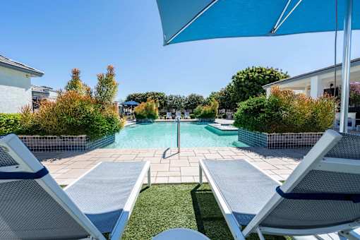 Pool deck lounge chairs with sun umbrella at Vistoria On Greenway Apartments, Arizona, 85379