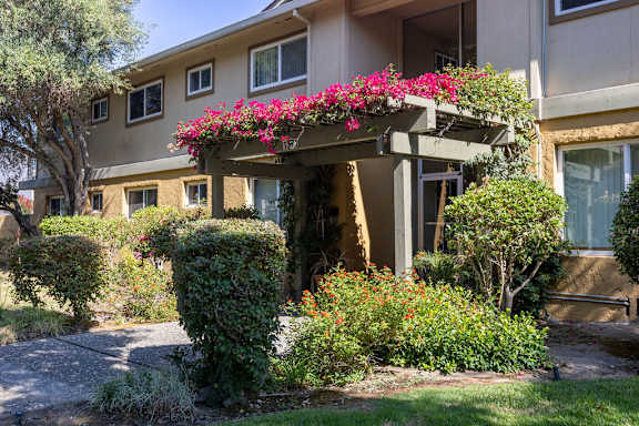 the front entrance of an apartment building with pink flowers on a porch