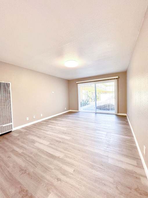 an empty living room with hardwood flooring and a sliding glass door
