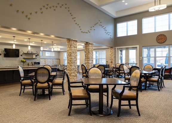 a large dining room with tables and chairs and a kitchen