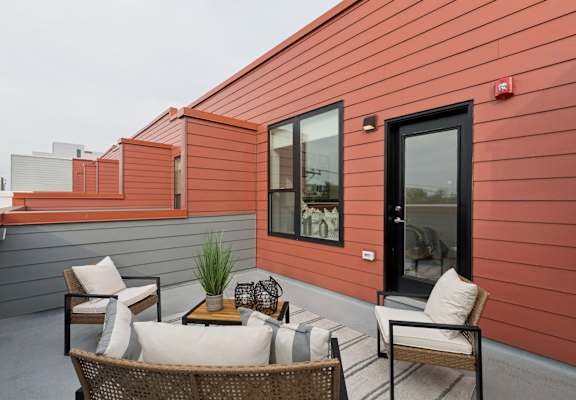 A patio with a table and chairs is on a red building.