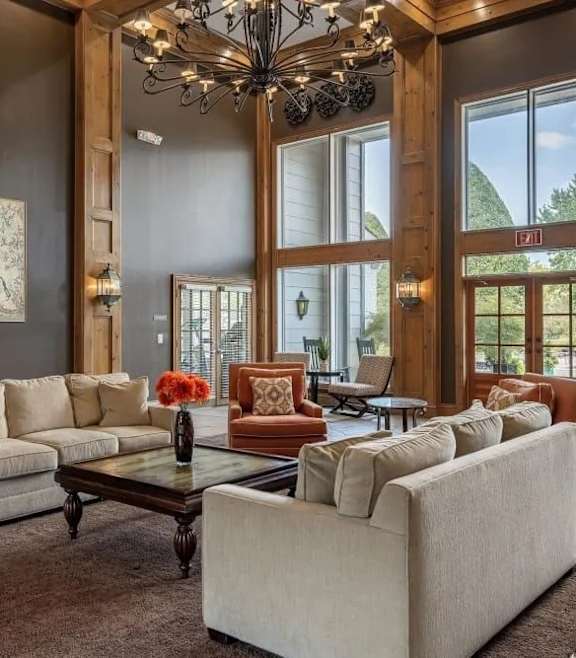 A large, well-lit living room with a chandelier, sofas, and a coffee table.
