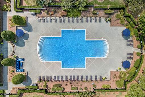 A large blue swimming pool surrounded by a brick patio and a grassy area.