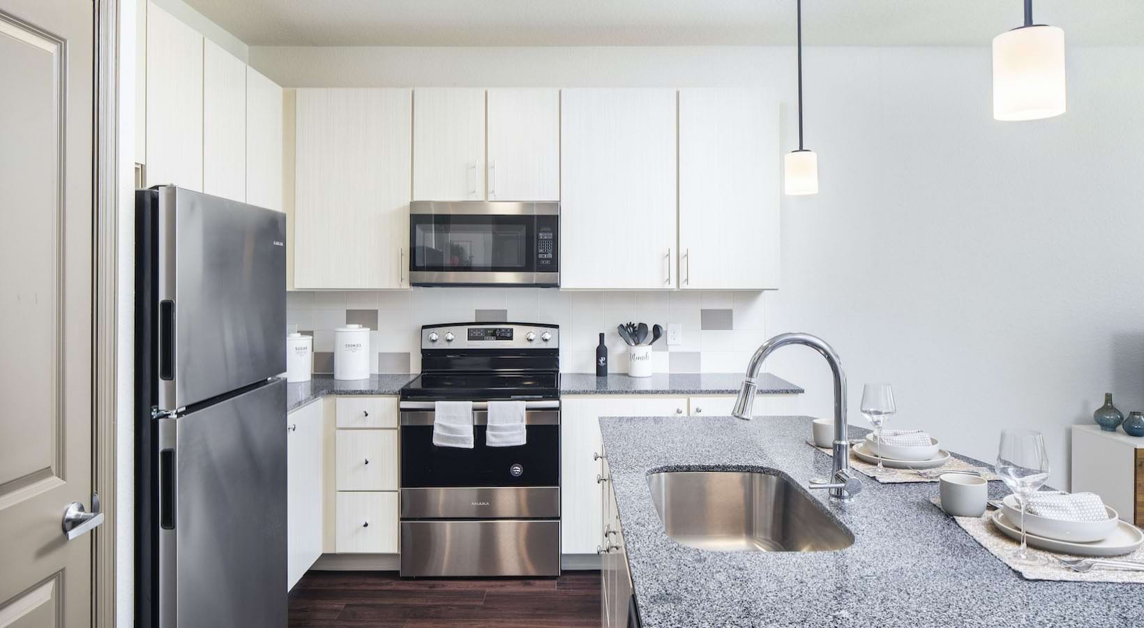 ChampionsGate, FL, Luxury Apartments Near Walt Disney World - Preserve at ChampionsGate - Kitchen with a Granite Countertop, Sleek Cabinetry, Stainless Steel Appliances, and Pendant Lights.