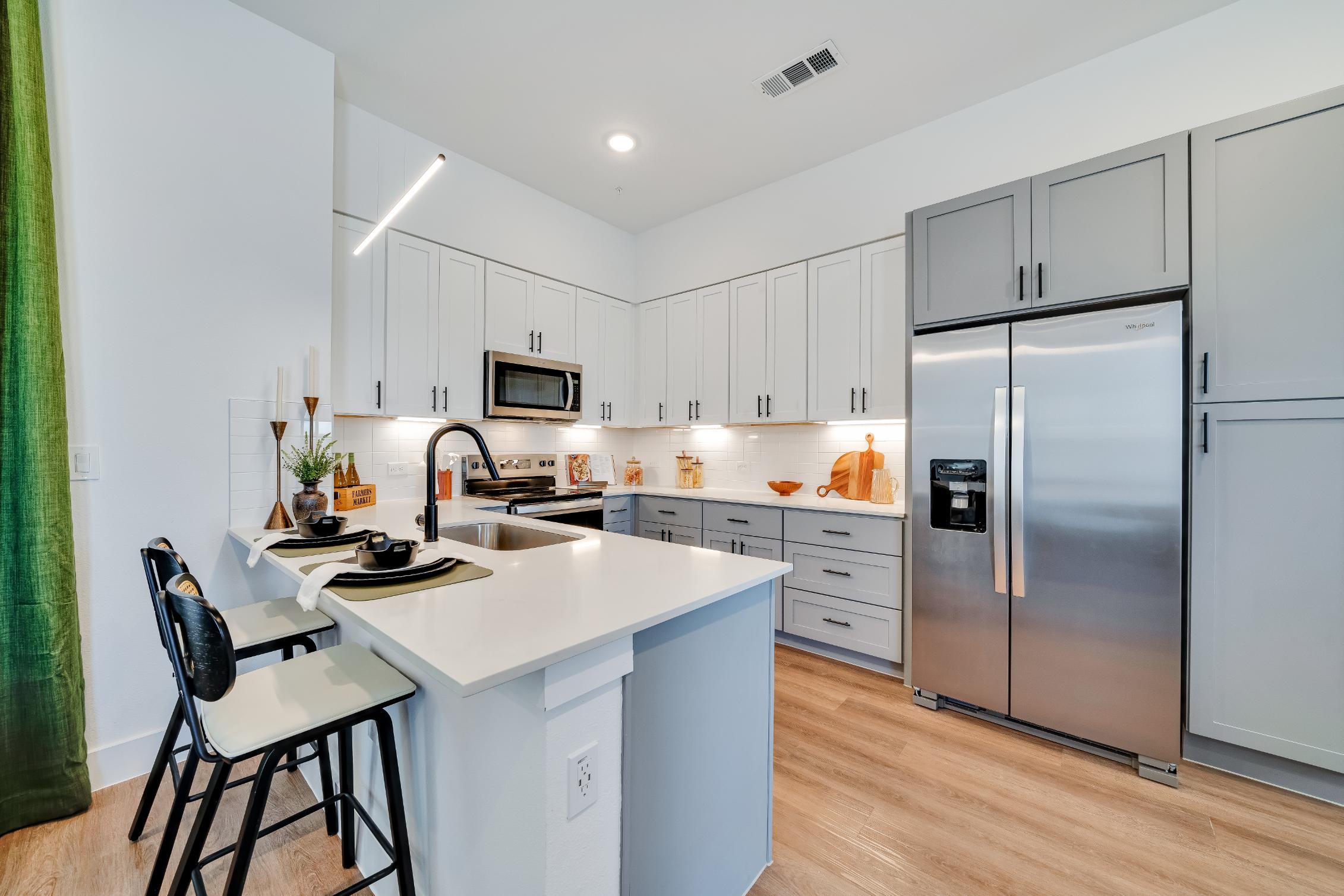 Stainless steel appliances inside a home's kitchen with a breakfast bar at The parcHAUS at Mustang Drive