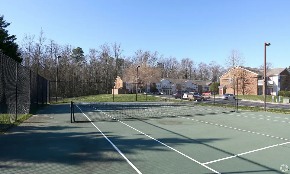 Inviting tennis court with a scenic backdrop and nearby residential buildings, perfect for outdoor recreation.