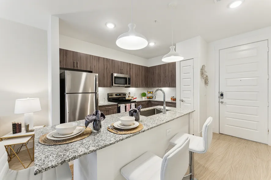 large upscale kitchen with stainless steel appliances a large bar, stools, and other modern features