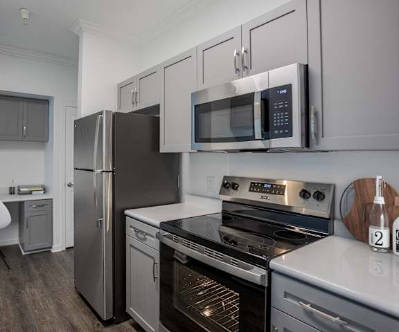 A modern kitchen with a stainless steel refrigerator, microwave, and oven.