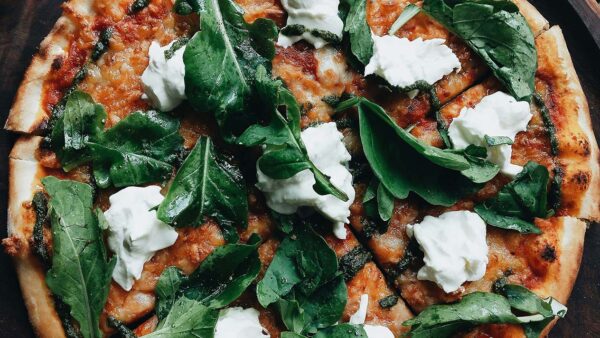 Pizza with crispy crust, sauce, cheese, and basil leaves.