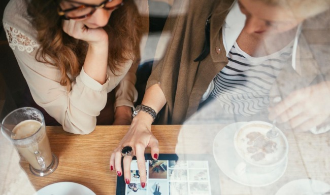 a couple of women sitting at a table with food and drinks