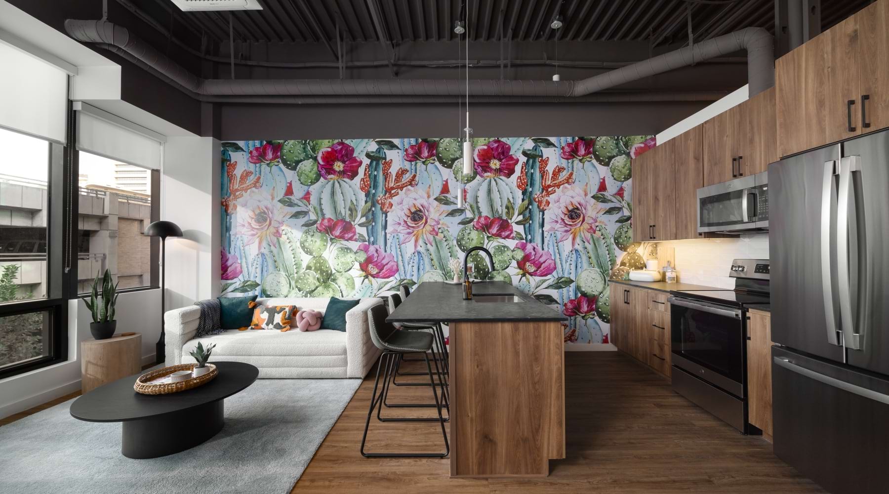 Modern Phoenix apartment interior featuring an open-concept kitchen, living room, wood cabinets, kitchen island, and a colorful cactus mural accent wall.