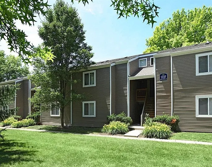 Charming apartment exterior surrounded by lush greenery and vibrant landscaping, inviting you to a serene living environment.