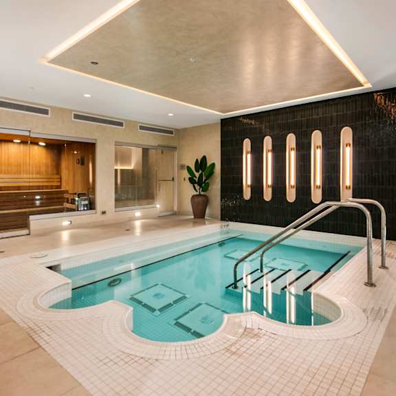 A large indoor swimming pool with a tiled edge and a metal ladder.