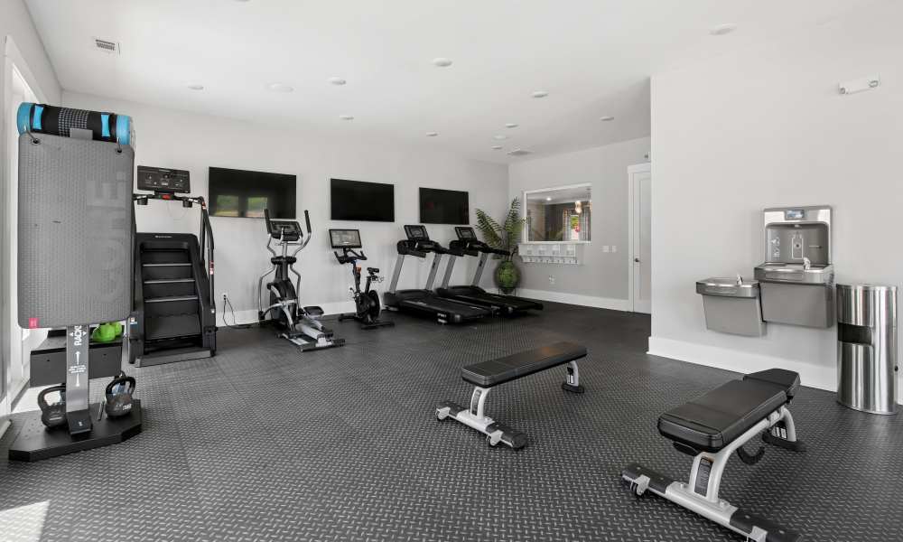 Modern fitness center with cardio machines, free weights, and water fountain at Everett at Port Wentworth in Port Wentworth, Georgia