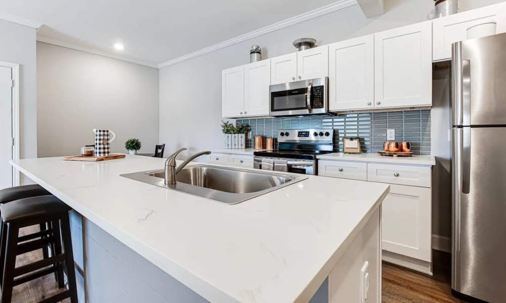 Modern kitchen with granite countertops, stainless steel appliances, and open layout featuring a large island at Everett at Port Wentworth in Port Wentworth, Georgia