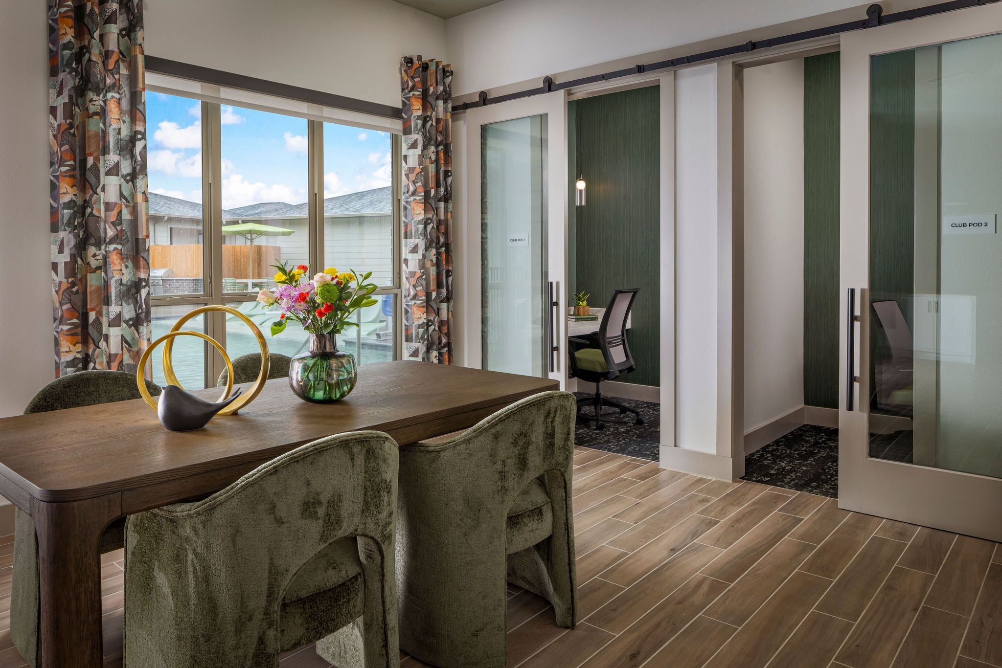 Modern, stylish interior with a dining table, floral centerpiece, and glass-paneled meeting rooms.