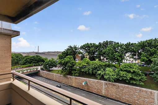 A view from a balcony overlooking a road and greenery.