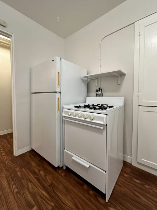 an empty kitchen with a white stove and refrigerator