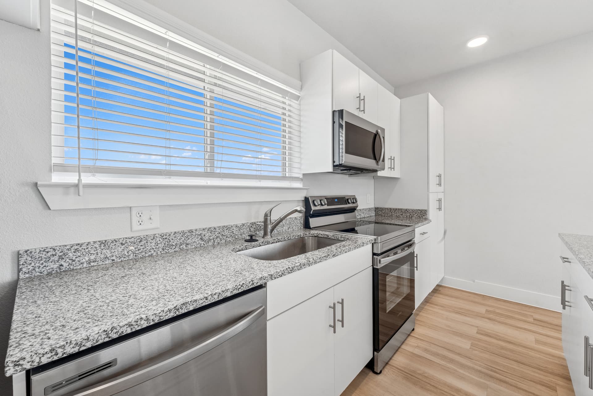 Granite countertop and stainless steel appliances in bright kitchen at Ensign Apartments