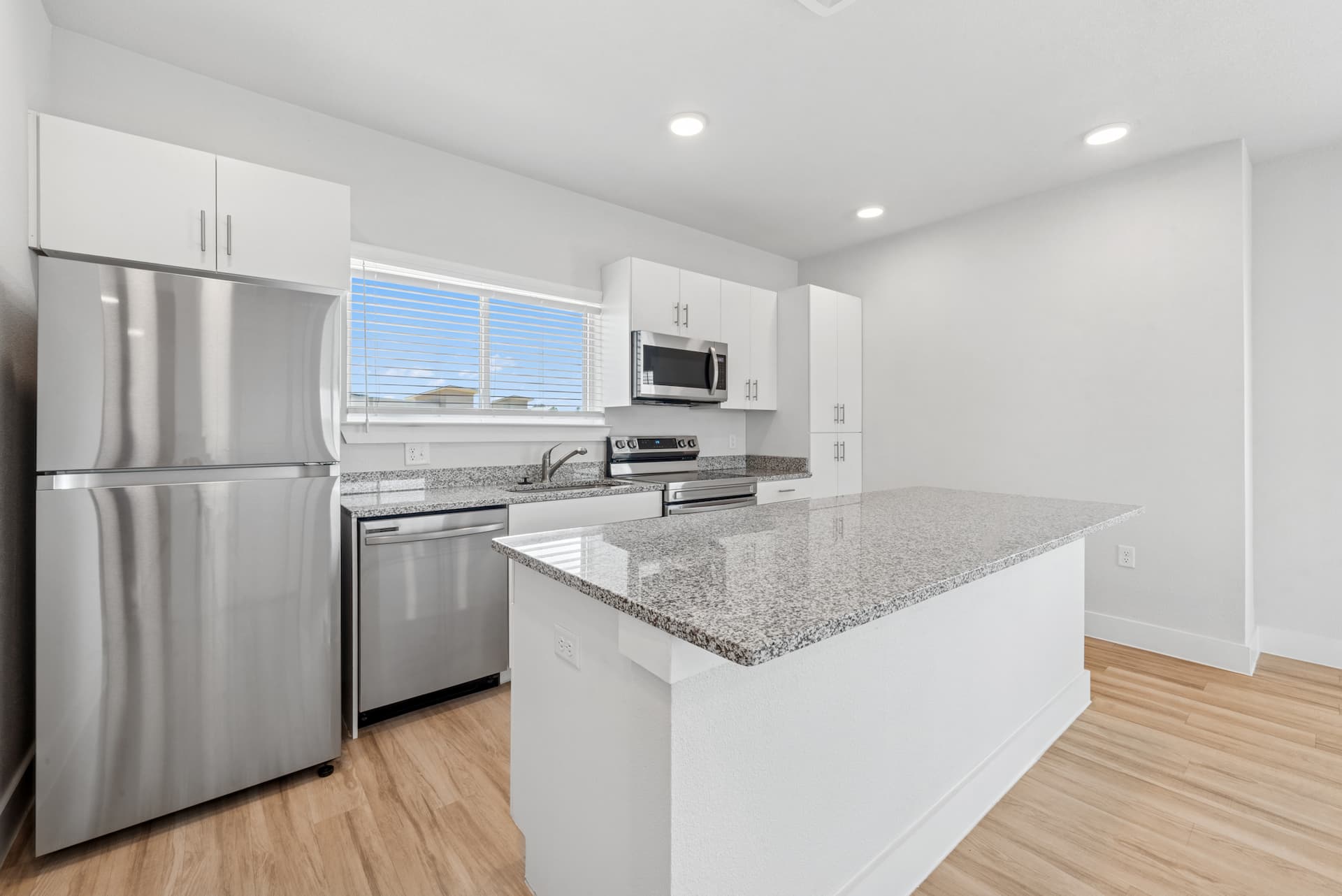 Kitchen view with stainless steel fridge, oven, microwave, and granite counters