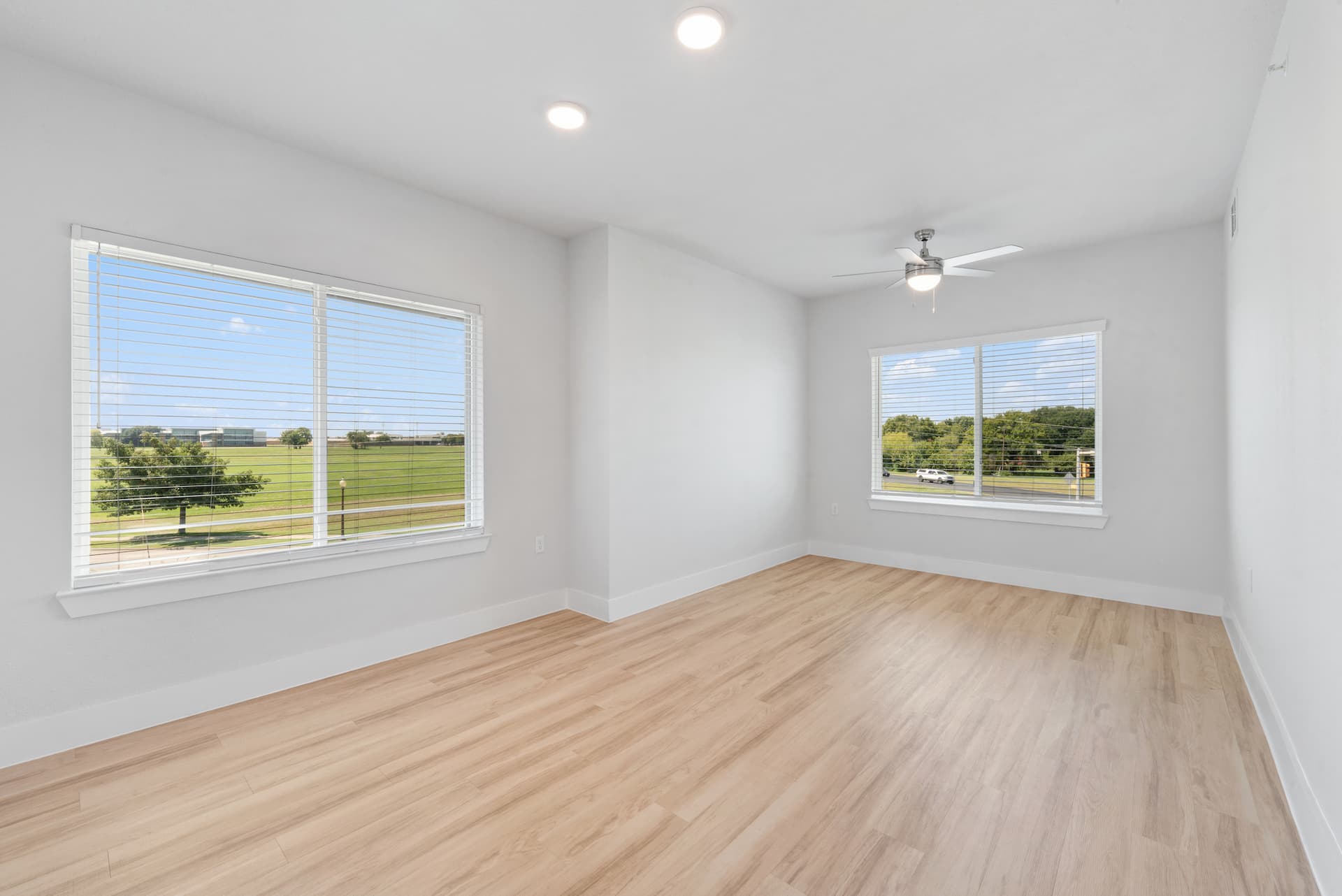 Spacious living area with wood-style flooring and large windows at Ensign Apartments