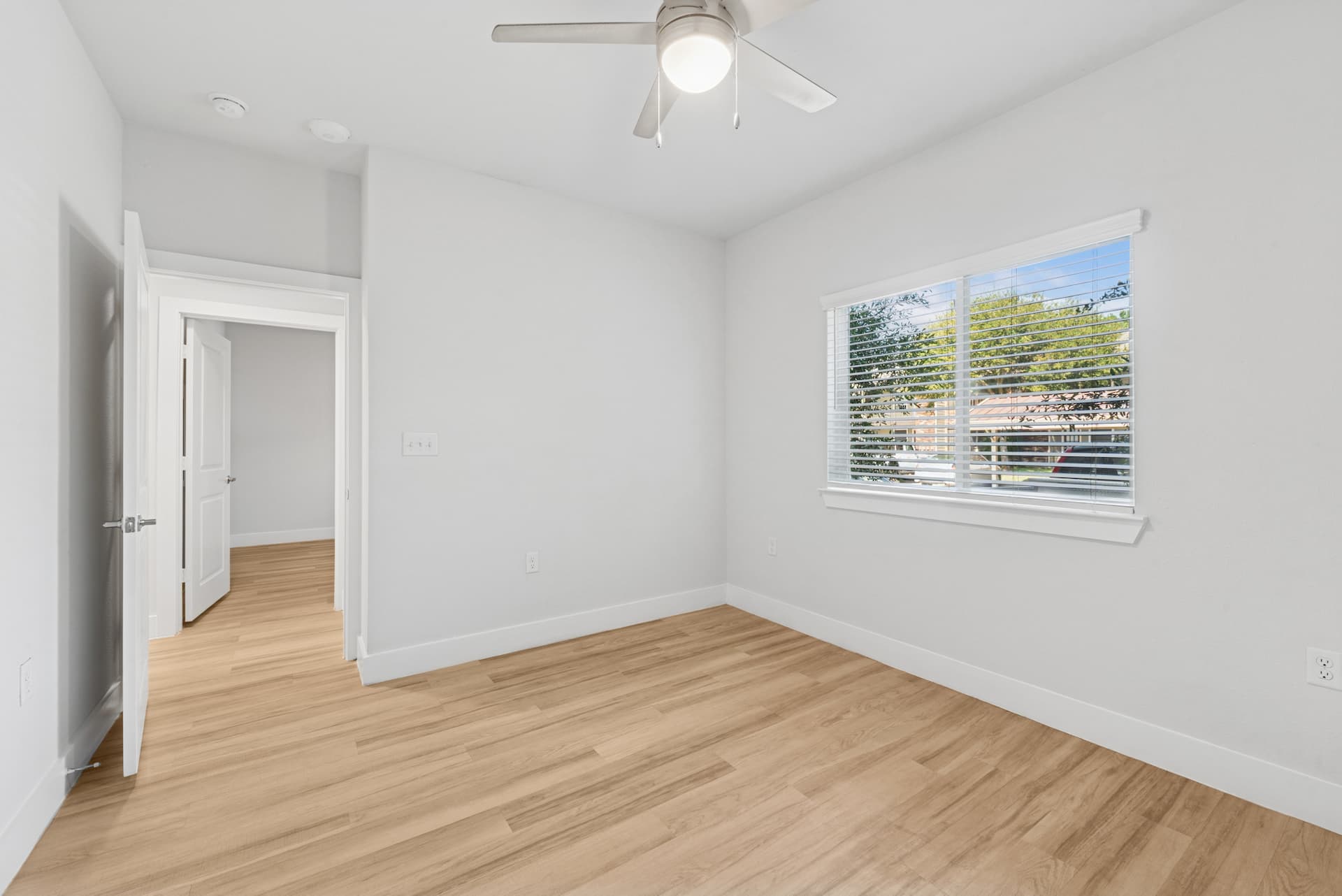 Ensign Apartments bedroom in Ennis, TX with wood-style flooring and ceiling fan.