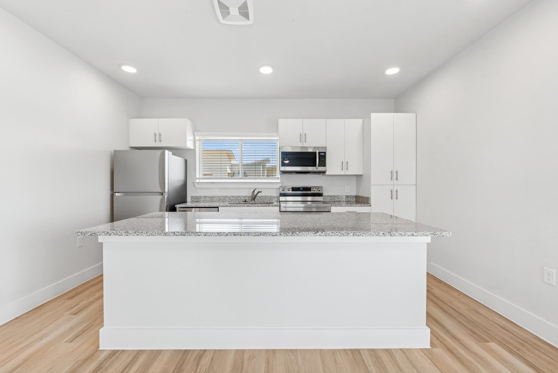 Modern kitchen with granite countertops, stainless steel appliances, and white cabinets