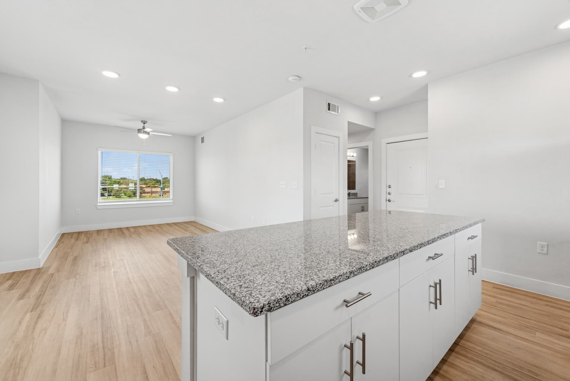 Spacious kitchen island with granite countertop and storage cabinets at Ensign Apartments
