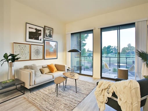 Scottsdale, AZ, Apartments for Rent - Dusk Scottsdale - Living Room with Wood-Style Flooring, Chair, Couch, Coffee Table, Decorative Area Rug, and Double Glass Sliding Patio Door.