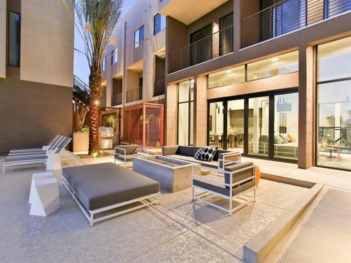 Apartments for Rent in Scottsdale, AZ - Dusk Scottsdale - BBQ with Fireplace, Outdoor Couch and Chairs with Tanning Chairs.