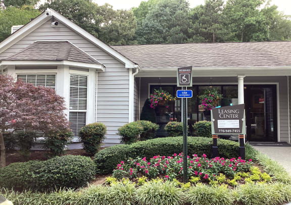 a building with white siding and awning with pink flowers and green vines on it