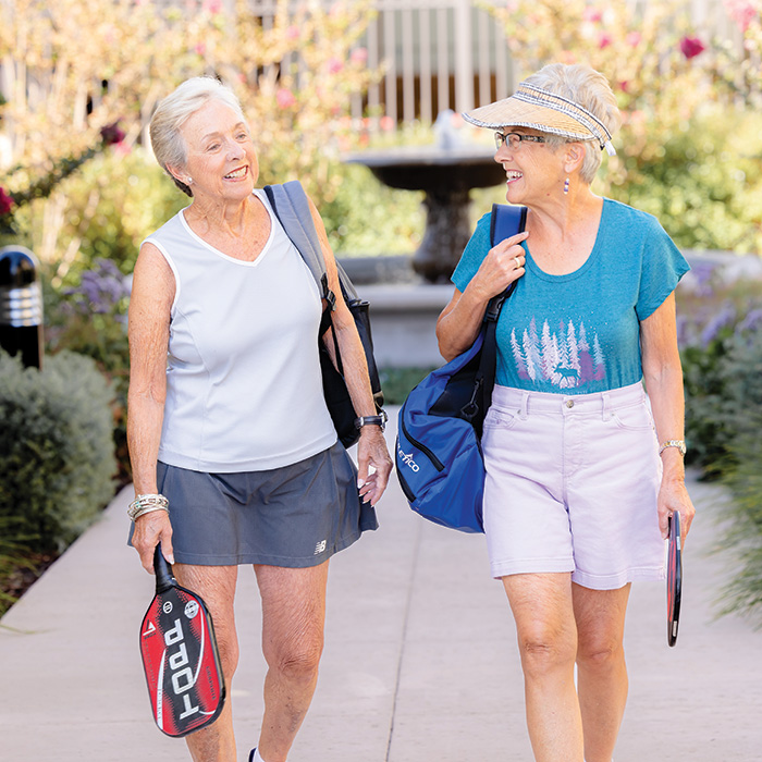 Two happy senior women on their way to play pickleball