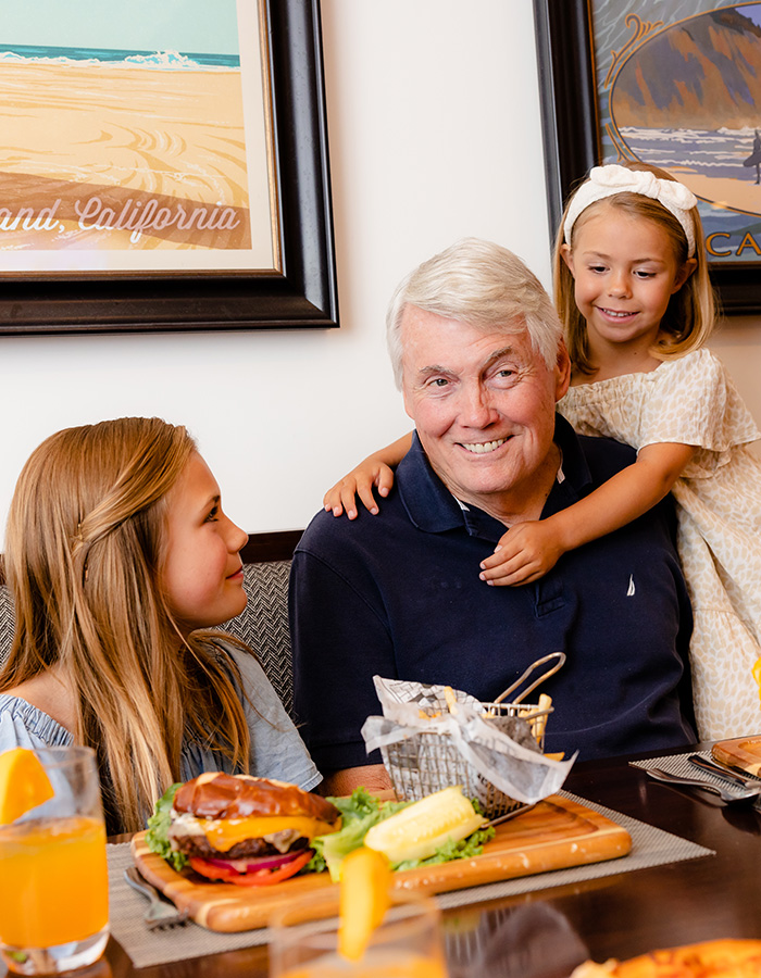 A grandfather enjoying hamburgers with his granddaughters