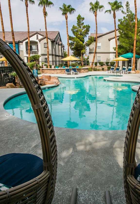 A swimming pool surrounded by palm trees and apartment buildings.