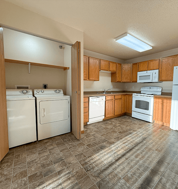 A kitchen with white appliances and brown cabinets.