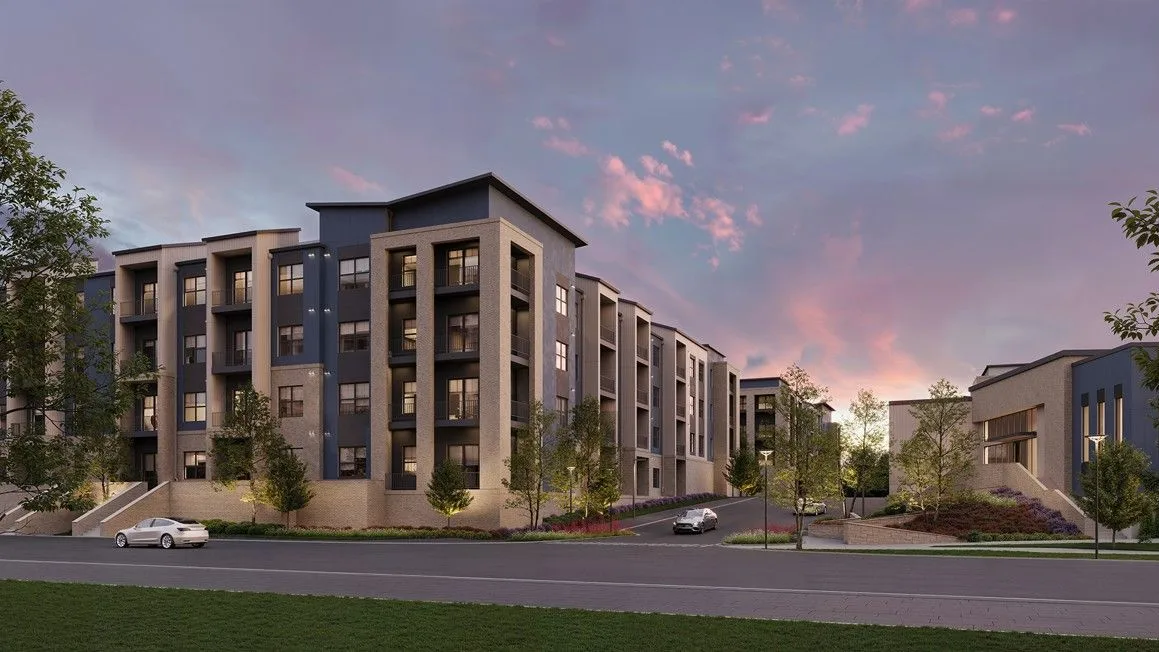 Modern apartment complex with landscaping and parked cars.