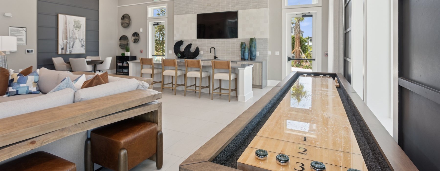a clubroom with a tv, shuffleboard table, chairs and tables