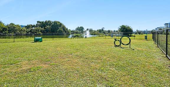 A park with a green playground set and a fence.