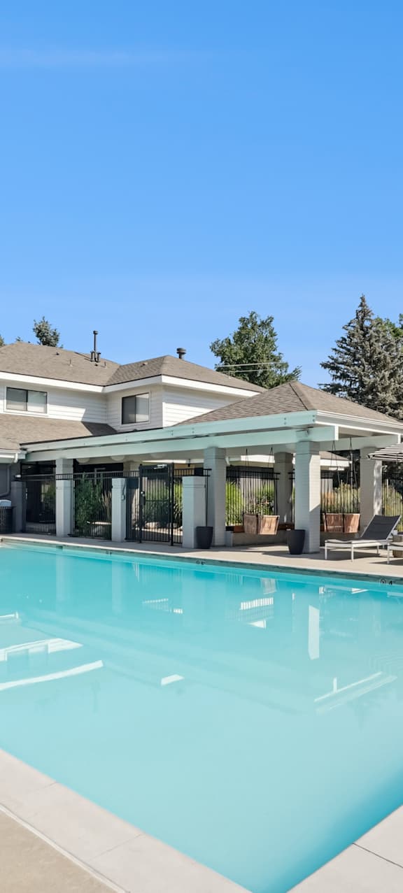 A large outdoor swimming pool with a diving board and lounge chairs.