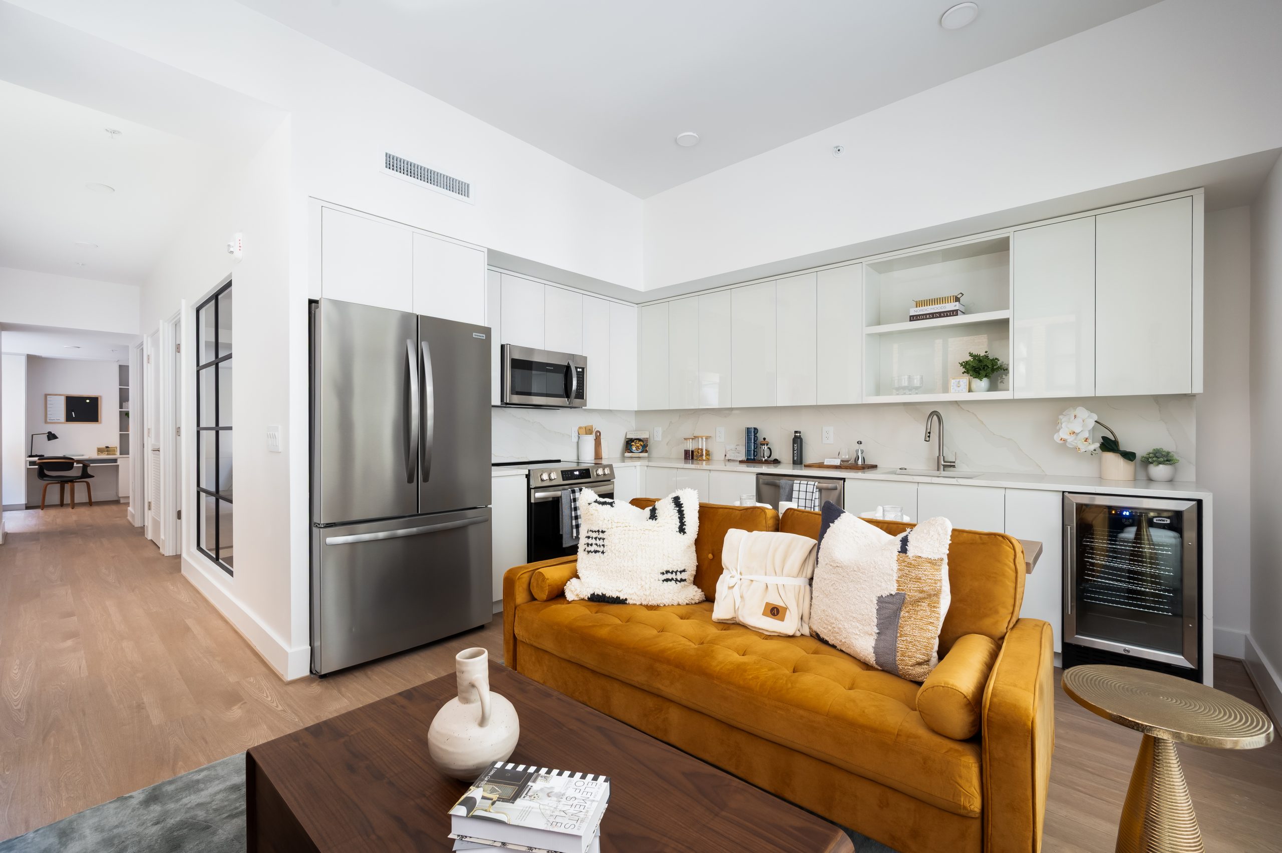 Kitchen with white cabinetry and living space with orange couch