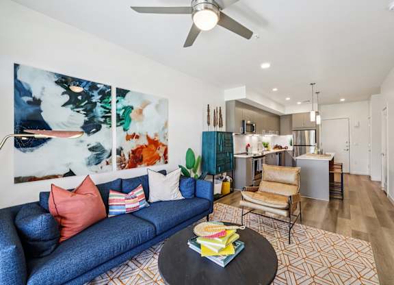 A living room with a blue couch and a painting on the wall.