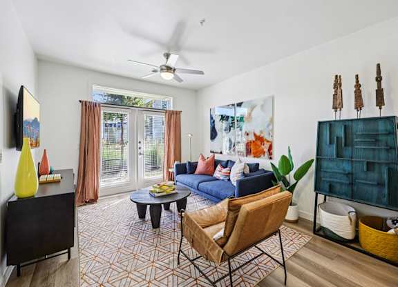 A living room with a blue couch and a yellow vase.