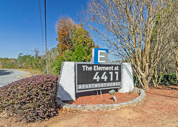 A sign for The Element at 4411 APARTMENT HOMES is in front of a road.