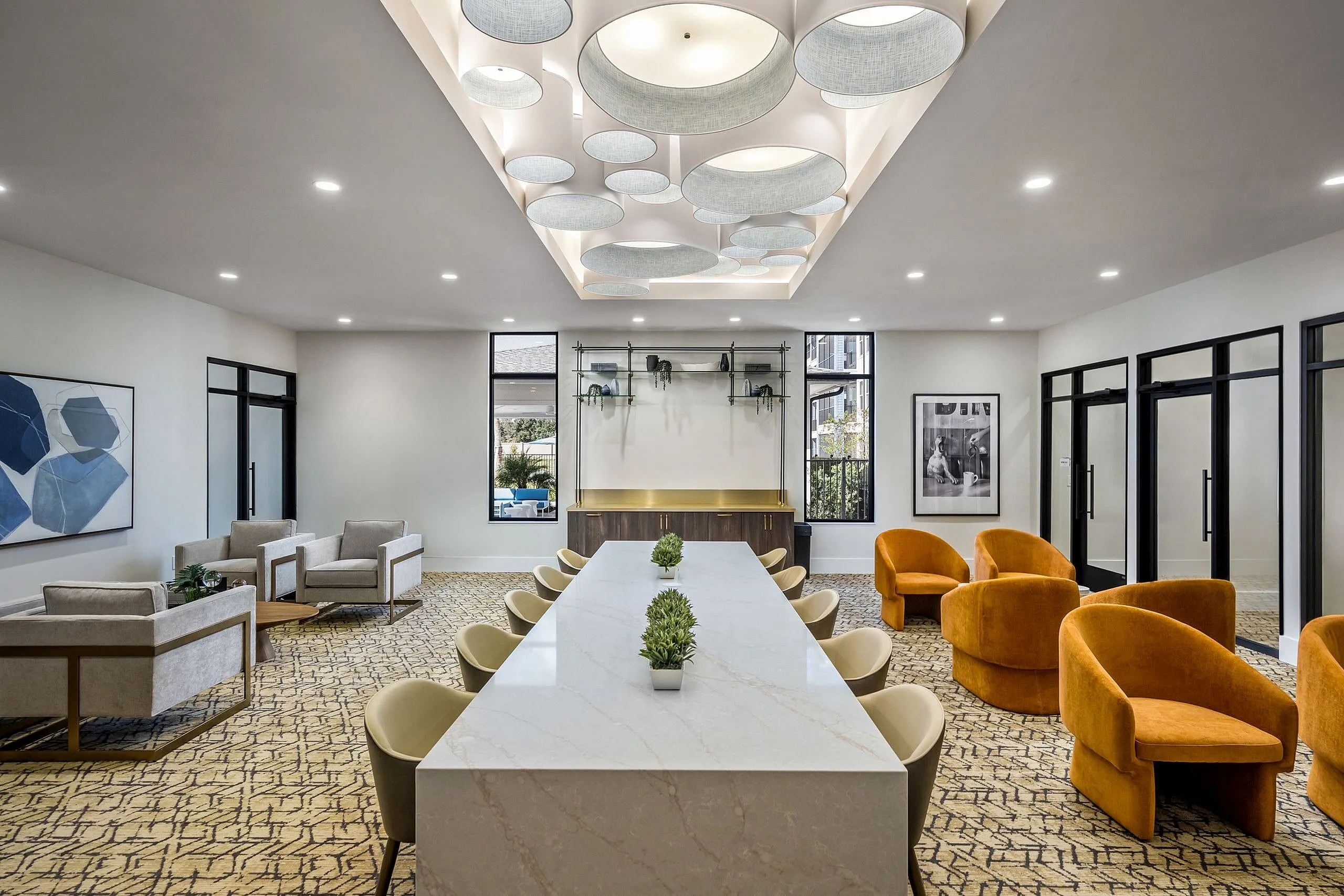 Elegant and modern meeting room with a large marble table, stylish seating, unique ceiling lights, and tasteful artwork.