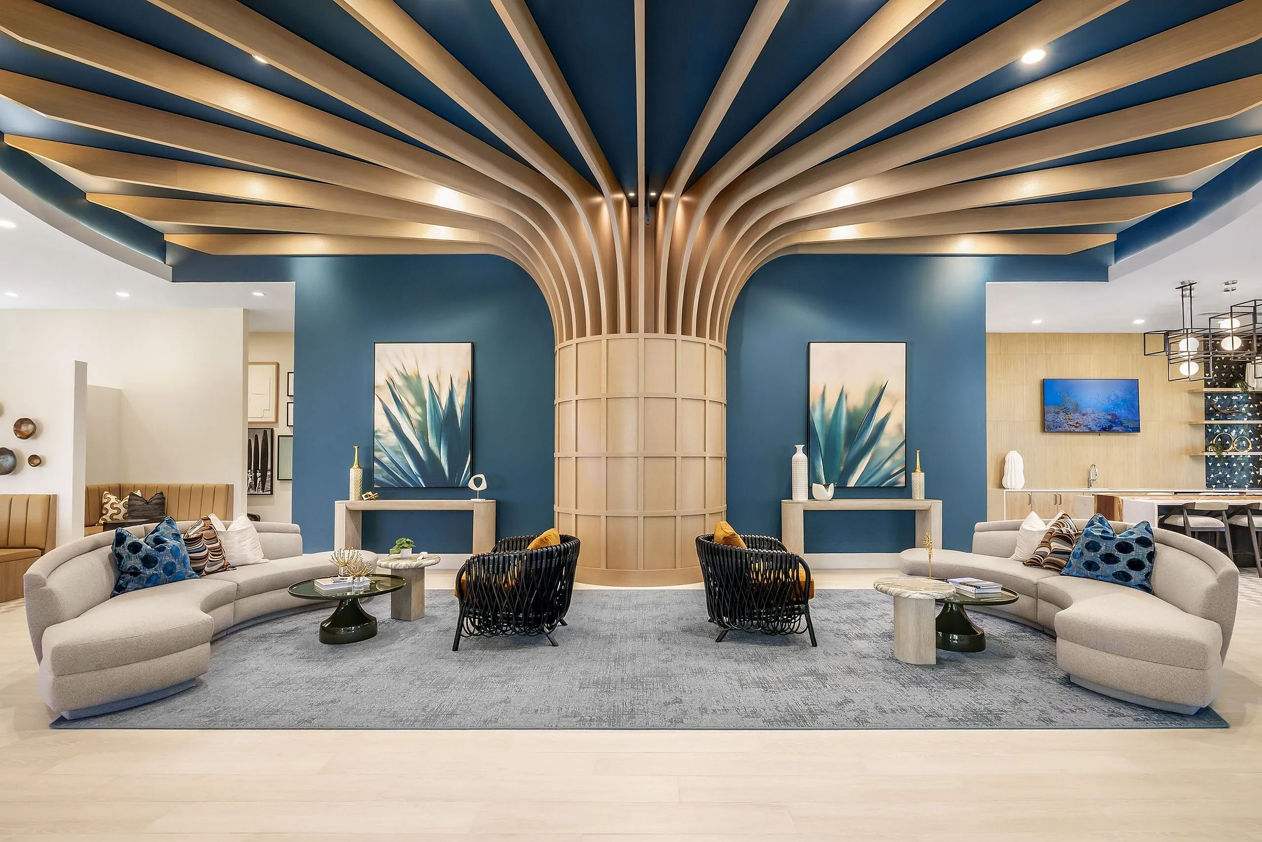 Luxurious modern lounge area featuring elegant curved sofas, stylish black woven chairs, and eye-catching geometric ceiling design, perfect for relaxation and social gatherings.