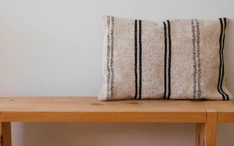 a wooden bench with a striped pillow on it