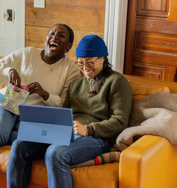Two people sitting on a couch with a laptop.