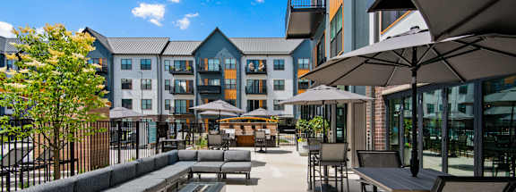 A patio area with tables and chairs and umbrellas.